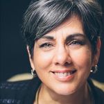A woman with short gray hair and earrings is smiling for the camera.